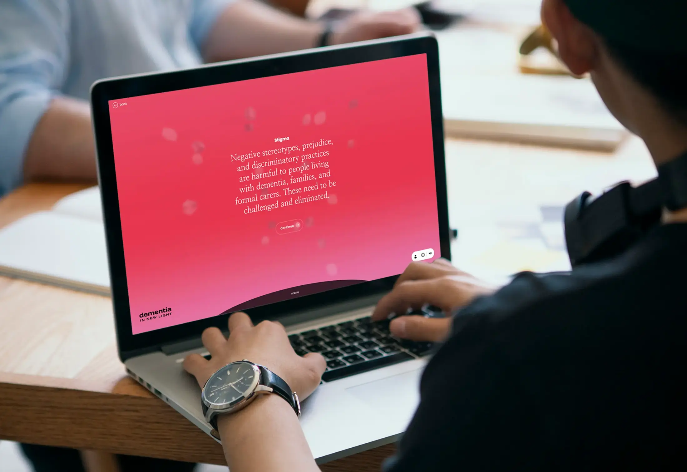 Person using a laptop displaying text about dementia stigma and a 