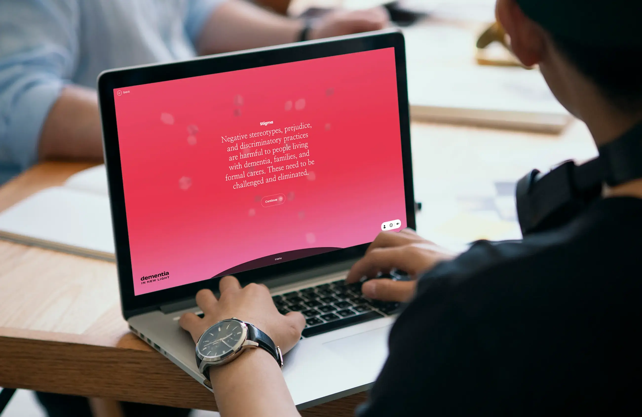 Person using a laptop displaying text about dementia stigma and a 