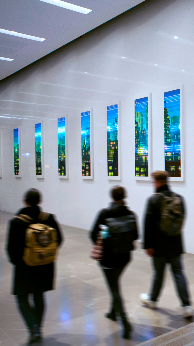 People walking past abstract city paintings in a gallery.