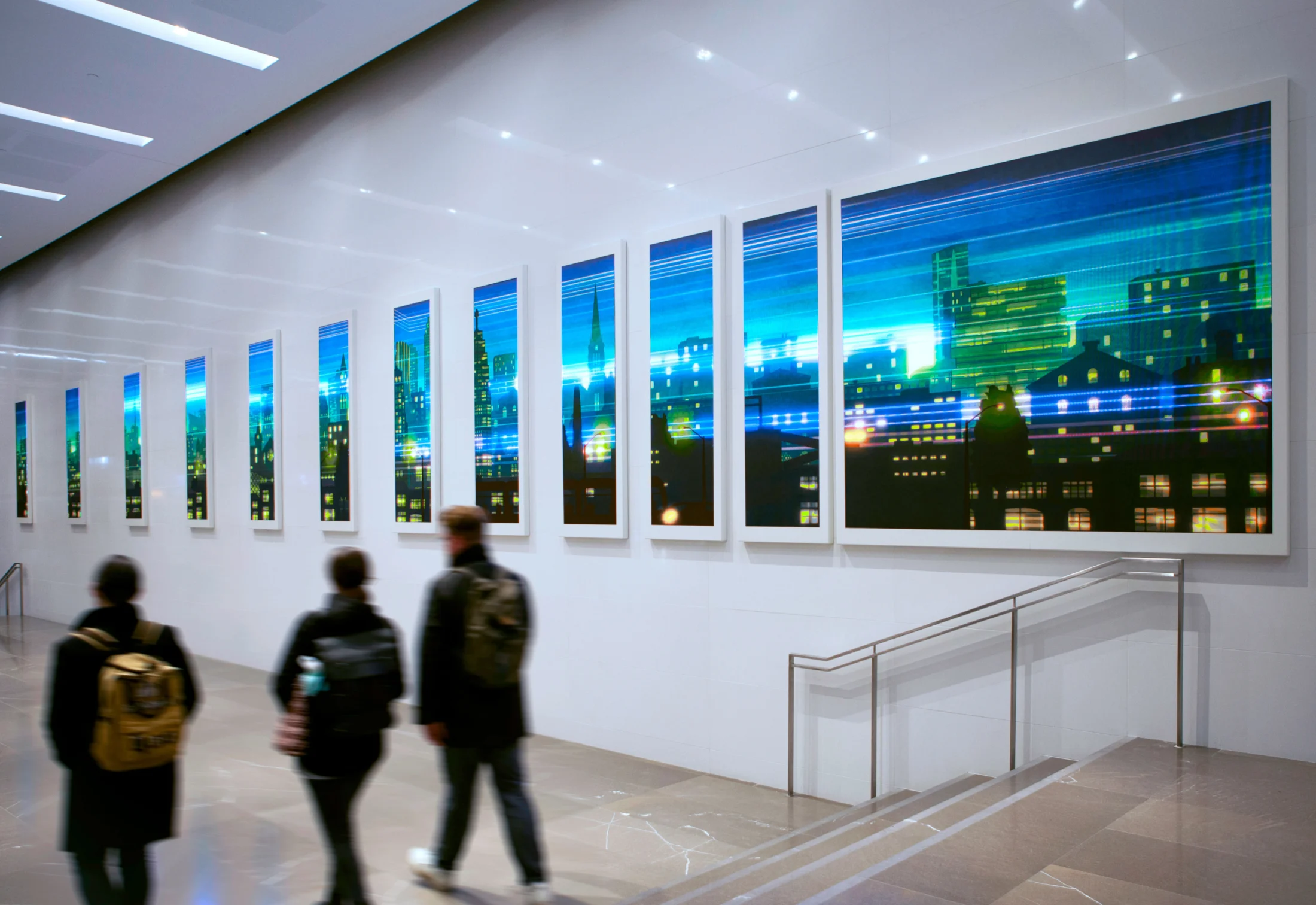 People walk past a series of vertical artworks depicting a colourful abstract cityscape at night.