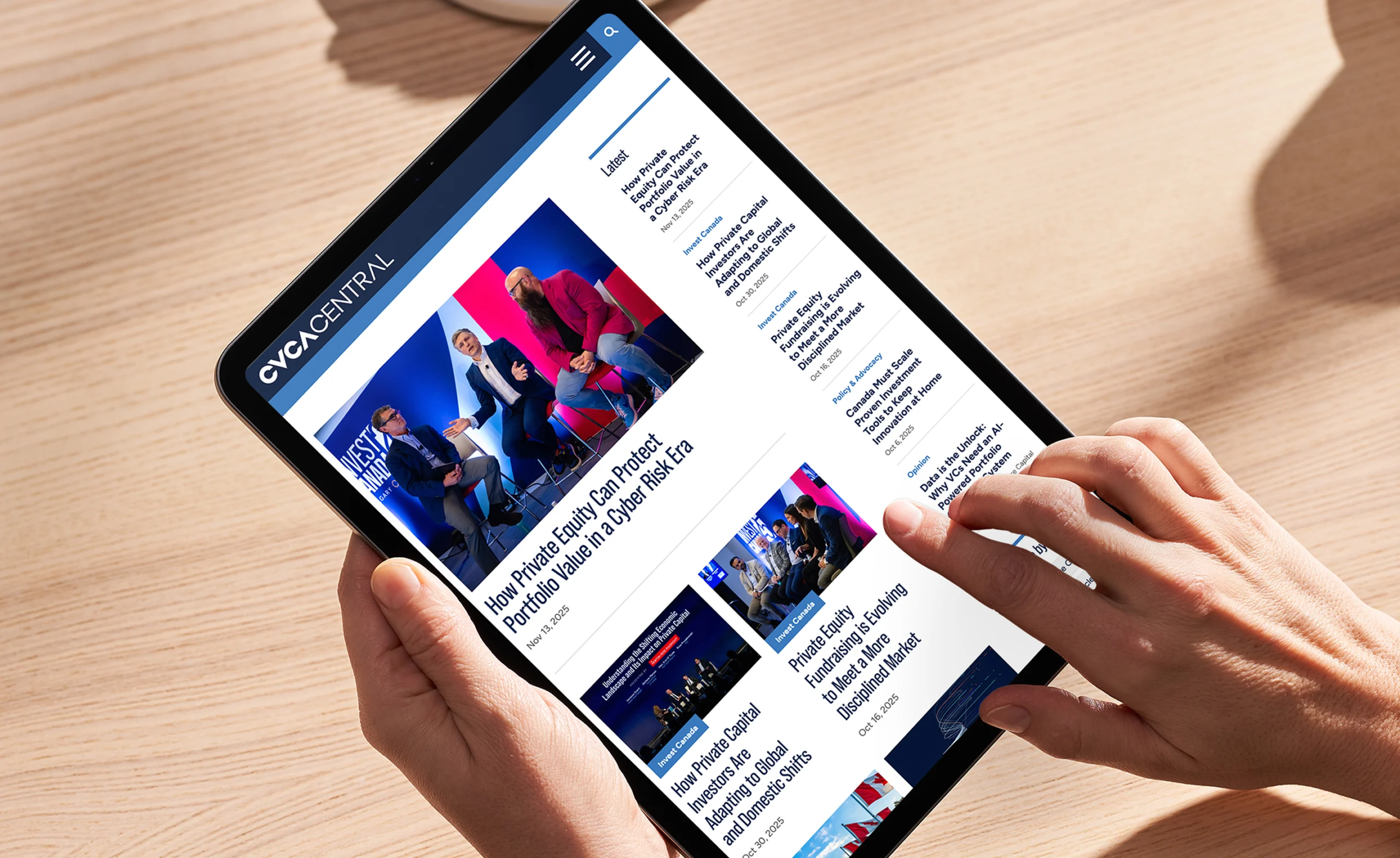 Hands holding a tablet displaying the CVCA Central website with articles on private equity.